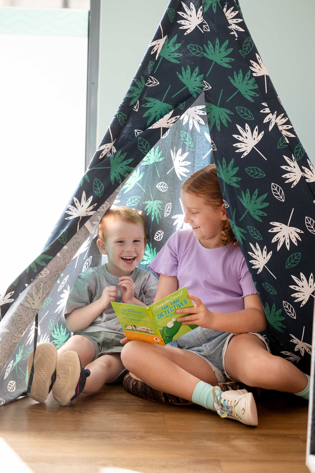Little boy and girl in a teepee inside reading